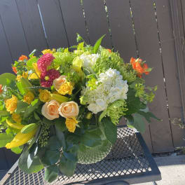 Mixed bouquet with yellow lilies, roses, and white hydrangeas in a vase
