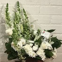 White floral arrangement with roses, lilies, and snapdragons in a low container