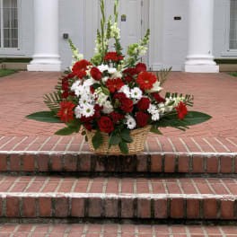 Basket arrangement of red and white flowers on brick steps