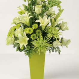 Green and white floral arrangement in a tall lime vase