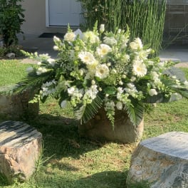 Large white floral arrangement with daisies and roses in an outdoor setting