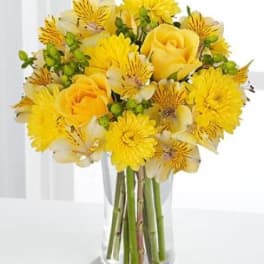 Yellow roses and daisies arranged in a clear glass vase