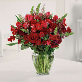 Red mixed flower bouquet in a clear glass vase