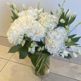 White hydrangea and lily bouquet in a clear glass vase