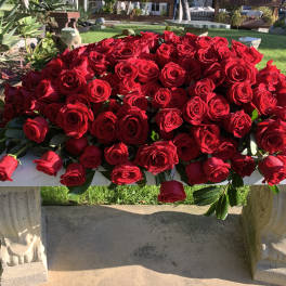 Large mound of red roses on a stone bench outdoors