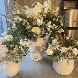 White floral arrangements in ceramic pitchers and vases