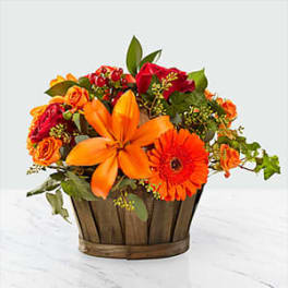 Orange and red flower arrangement in a wooden basket