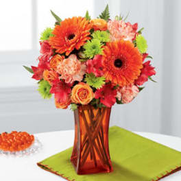 Orange and pink mixed bouquet in an amber glass vase