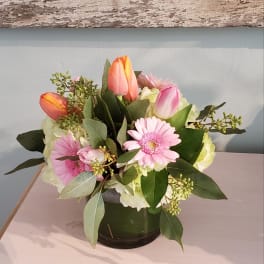 Pink gerbera daisies and tulips in a glass vase
