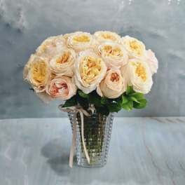 Peach and cream roses in a clear glass vase with a ribbon
