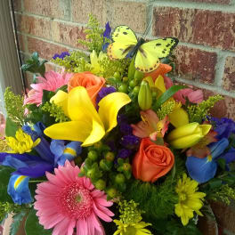 Colorful mixed bouquet with roses, lilies, daisies, and a butterfly pick