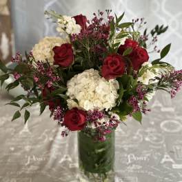 Red roses and white hydrangeas in a glass vase