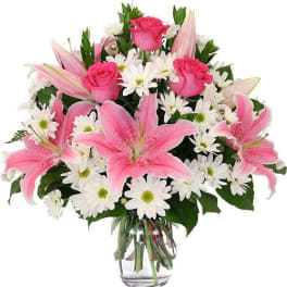 Pink lilies and roses with white daisies in a glass vase
