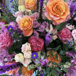 Bouquet of orange and pink roses with purple filler flowers