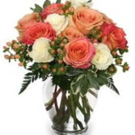 Bouquet of peach, pink, and white roses in a clear glass vase