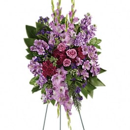 Standing floral spray with purple and pink flowers on a wire easel