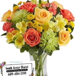 Mixed bouquet of roses and yellow flowers in a clear glass vase