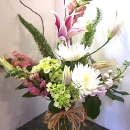 Tall mixed bouquet with white daisies and pink lilies in a glass vase