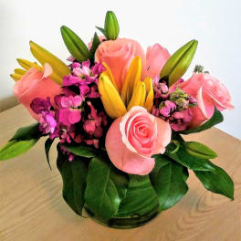 Pink roses and yellow lilies arranged in a glass vase