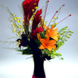 Orange lilies and red tropical flowers in a tall vase