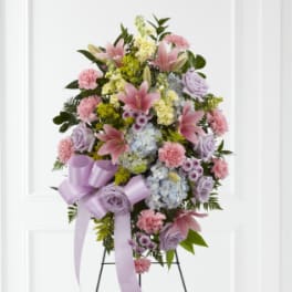 Standing floral spray with pink lilies, carnations, and lavender roses on an easel