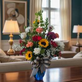 Mixed bouquet in a blue vase with a striped ribbon