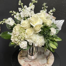 White roses and hydrangeas arranged in a silver vase