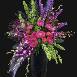 Bright pink and purple floral arrangement in a tall dark vase