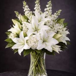 White lilies and hydrangeas arranged in a clear glass vase