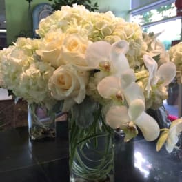 White roses and orchids arranged in a clear glass vase