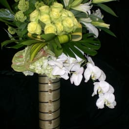 Bouquet of pale yellow roses, white lilies, and white orchids in a tall vase