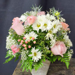 Pink and white flowers arranged in a white container