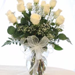 Cream rose bouquet in a glass vase with a sheer ribbon bow