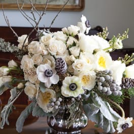 White floral arrangement with roses and anemones in a silver vase