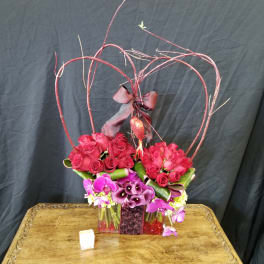 Heart-shaped rose arrangement with purple orchids in a vase