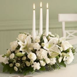 White floral centerpiece with three lit taper candles