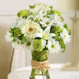 White daisies and lilies arranged in a glass vase with twine wrap