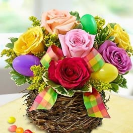 Colorful roses arranged in a woven basket with pastel Easter eggs