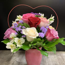 Mixed roses and white alstroemeria in a pink vase with a heart handle