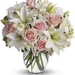 Pink roses and white lilies arranged in a clear glass vase