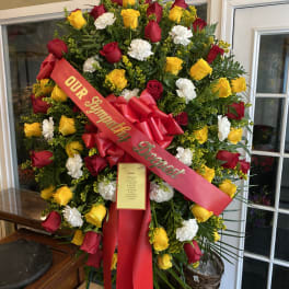 Large standing wreath of red, yellow, and white roses with a red ribbon