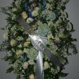 Large standing floral wreath with white and blue flowers and a satin ribbon