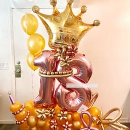 Gold crown balloon display with rose-gold number 18 balloons and yellow balloons