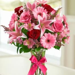 Pink and red mixed bouquet in a glass vase with a ribbon