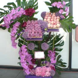 Tall floral display with pink orchids, roses, and large tropical leaves