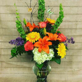 Colorful bouquet with lilies, roses, daisies, and hydrangea in a glass vase