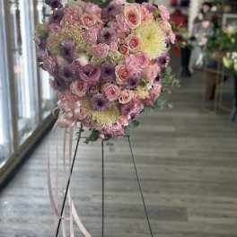 Heart-shaped bouquet of pink and purple flowers on a stand