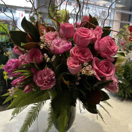 Pink roses and carnations in a glass vase with curly branches