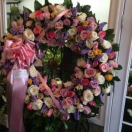 Large floral wreath of pink, white, and purple roses with a pink ribbon