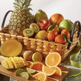 Basket of assorted fruit with sliced citrus and mango on a cutting board